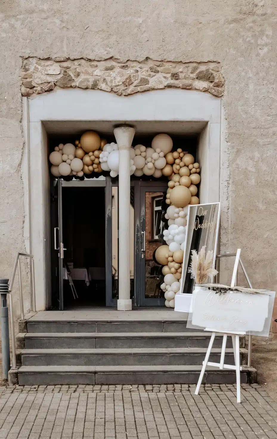 Ballonbogen in Weiß und Gold am Eingang einer Hochzeitslocation